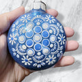 blue Christmas ornament decorated with white snowflakes and blue dots.