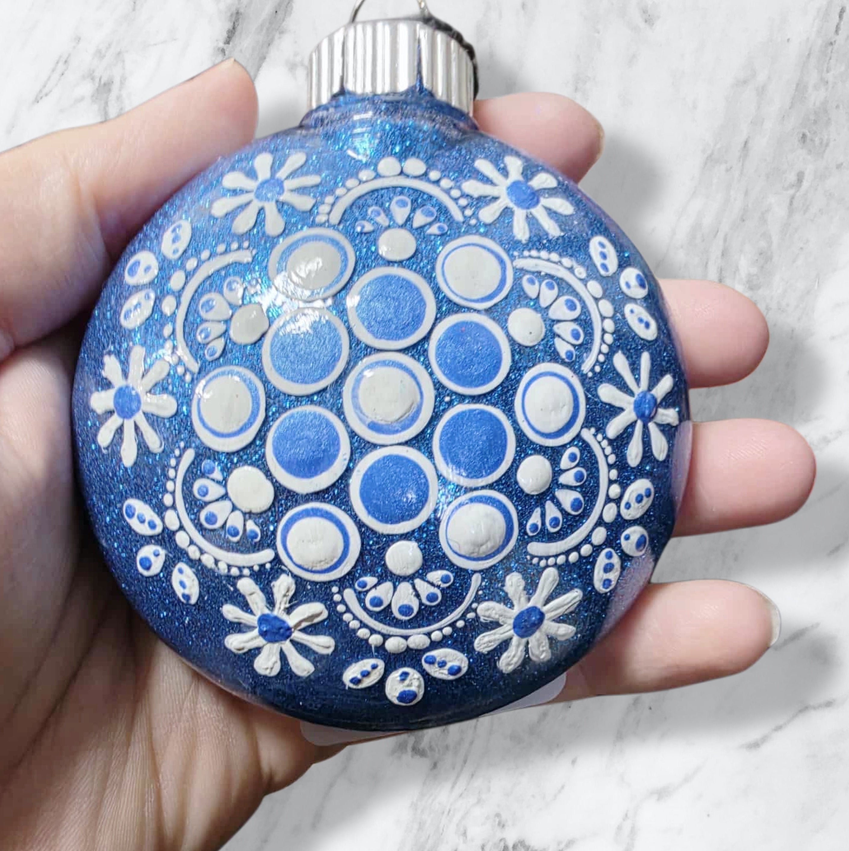 blue Christmas ornament decorated with white snowflakes and blue dots.