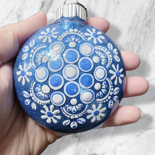 blue Christmas ornament decorated with white snowflakes and blue dots.